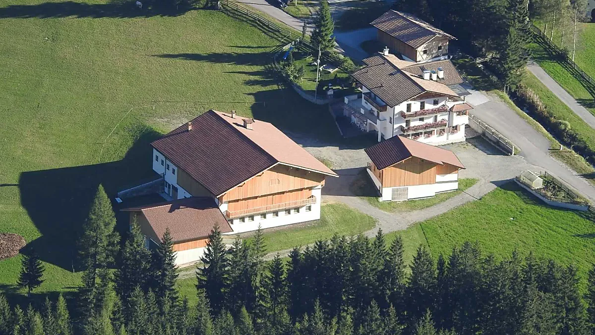 Der Huterhof im Sommer: Hier sehen Sie das neu erbaute Wirtschaftsgebäude und das Wohnhaus mit dem dahinterliegenden Spielplatz.