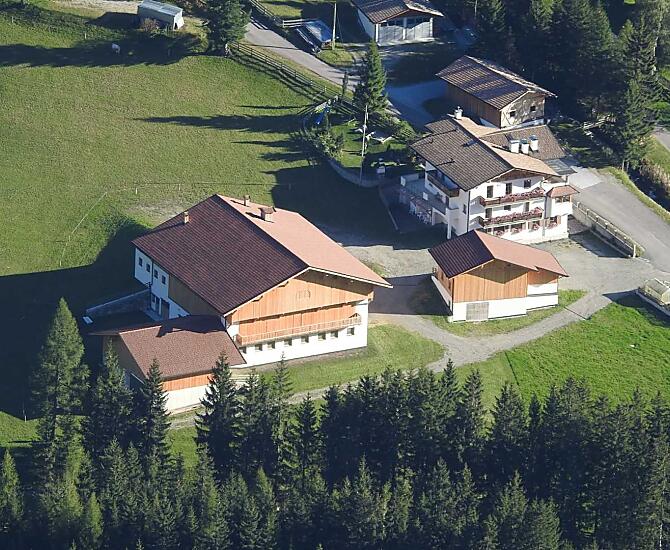 Der Huterhof im Sommer: Hier sehen Sie das neu erbaute Wirtschaftsgebäude und das Wohnhaus mit dem dahinterliegenden Spielplatz.