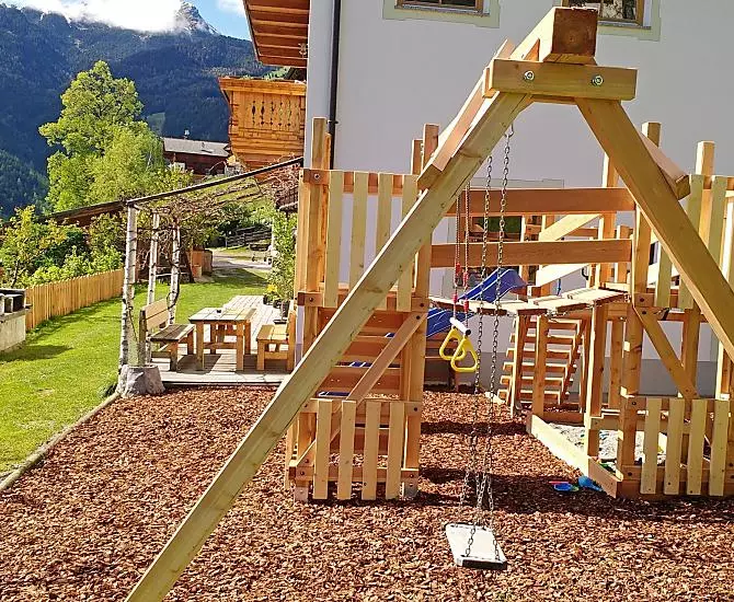 Der Spielplatz, im Hintergrund die Gartenlaube und der Grill.