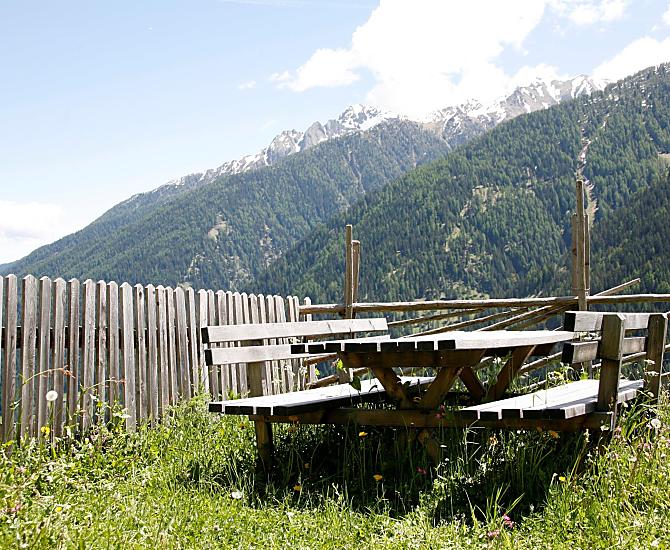 Sitzbereich mit Aussicht auf das Tal, den See und die Berge.