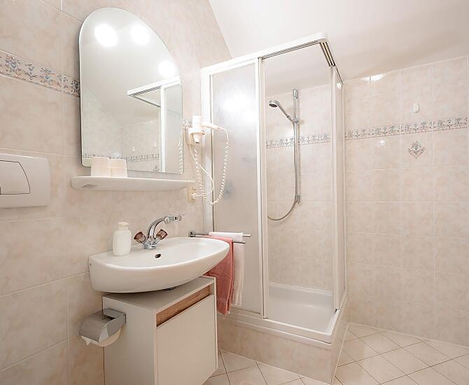 Badezimmer mit Dusche, WC und Haartrockner.