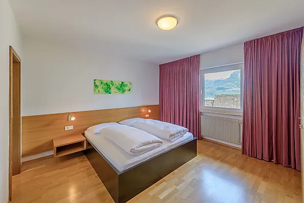 Geräumiges Doppelzimmer mit dreiteiligem Schrank, Holzboden, Bettenlänge 200 cm, Safe, direktem Zugang zum Badezimmer und Blick ins Tal.