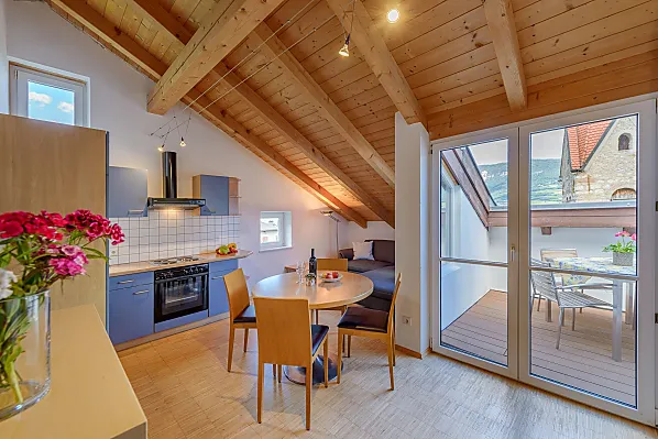 Wohnraum mit Küche, Tramin Blick, Couch, Fernseher und Dachterrasse auf Kirchturmhöhe mit Esstisch