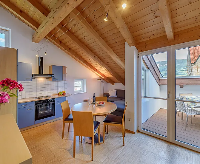 Wohnraum mit Küche, Tramin Blick, Couch, Fernseher und Dachterrasse auf Kirchturmhöhe mit Esstisch