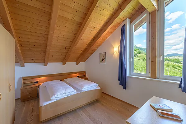 Schlafzimmer mit herrlichem Ausblick auf Tramin, den Poolbereich, in die Weinberge, in die Berge bis zur Sarner Scharte und aufs Weisshorn